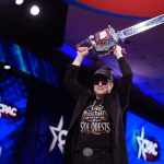 CEO of Tesla and SpaceX Elon Musk holding a chainsaw above his head.
