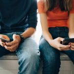 couple sitting, texting on smartphones